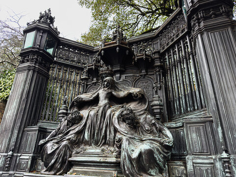 Ornate bronze Queen Alexandra Memorial sculpture and decorative iron gate at Brompton Cemetery in London, UK