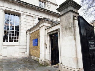 Naklejka premium Man sitting outside historic stone Marlborough House building entrance and gate in London, UK on overcast day