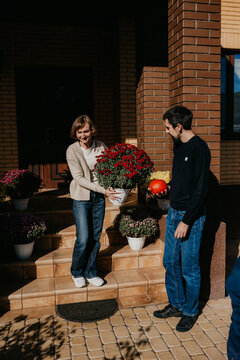 Couple decorating front porch with autumn flowers and pumpkin