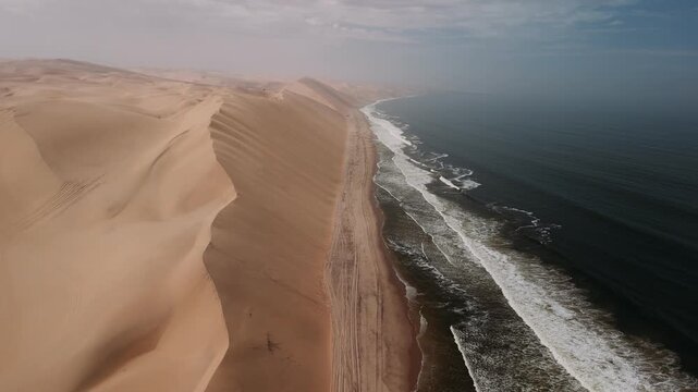 Aerial view of sandwich harbour in namibia where the desert sand dunes meet the atlantic ocean, creating a stunning landscape