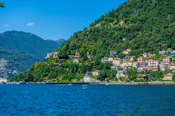 Fototapeta premium Como lake nature water resort. Multicolor houses on green hills. Italian travel. Italy green mountain village with villa home outdoor.