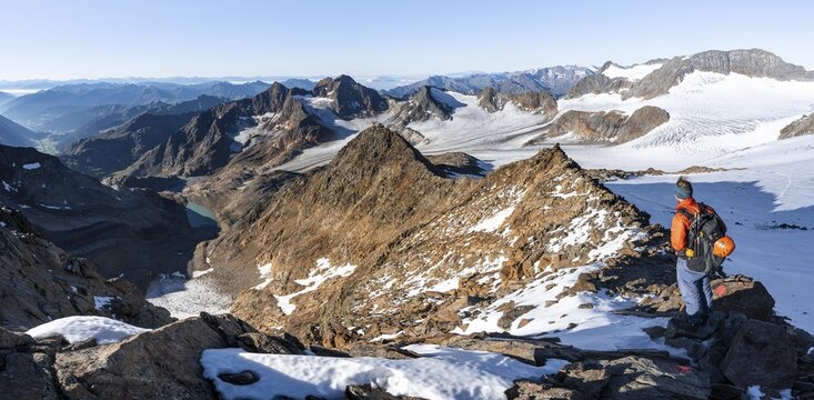 Mountaineer on a rocky ridge on the Wilder Freiger summit, behind him Signal summit and Becher summit with Becherhaus, picturesque high mountain landscape, view of &Uuml;beltalferner glacier and rocky mountain peaks K&ouml;nigshofspitz and Sonklarspitze, Stubai Alps, South Tyrol, Italy