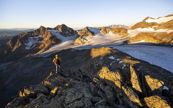 Mountaineers in front of a picturesque high mountain landscape at sunrise with alpenglow, glacier and rocky mountain peaks in the morning light, view at the Becher on mountain peak K&ouml;nigshofspitz and glacier &Uuml;beltalferner, Stubai Alps, South Tyrol, Italy