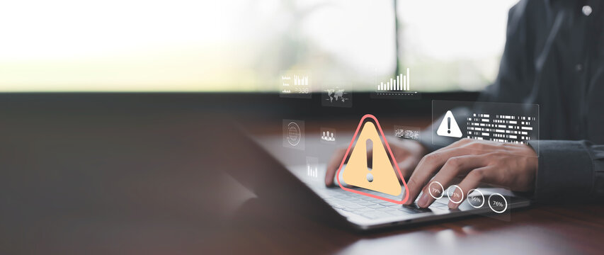 Business professional monitoring cybersecurity risks and system alerts on laptop with digital warning interface, risk management dashboard, threat detection, data protection, compliance monitoring and