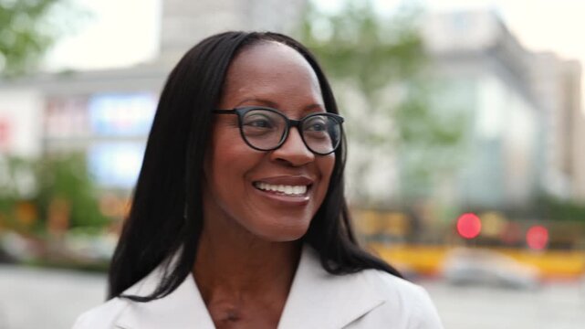 Elegant woman wearing glasses smiling in the city center
