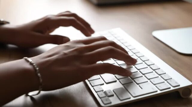 Close-up of female hands typing on white computer keyboard.