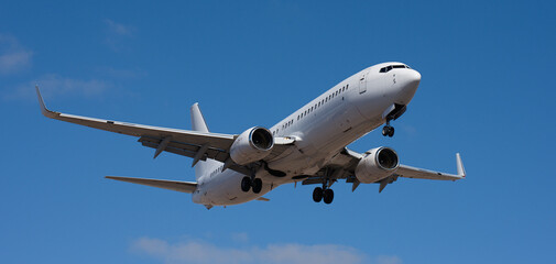 Fototapeta premium The plane lands. Airplane, passengers flying in the blue sky, preparing to land at the airport
