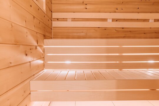 Wooden sauna interior showcasing smooth benches and warm ambient lighting textures in Finland