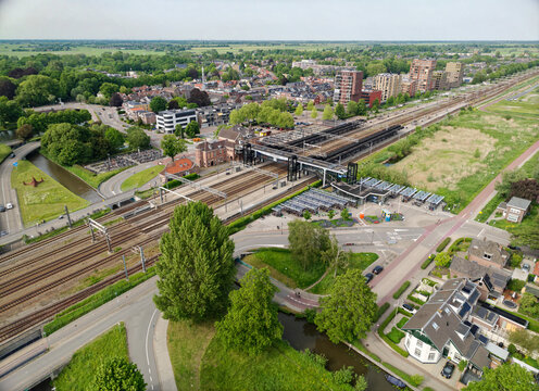 Aerial view Dutch Woerden public train station, railway tracks, urban buildings, and connecting roads