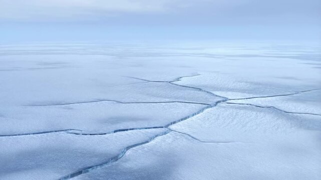 Expansive aerial view of a frozen landscape with intricate ice formations and cracks. Represents the beauty and fragility of polar environments