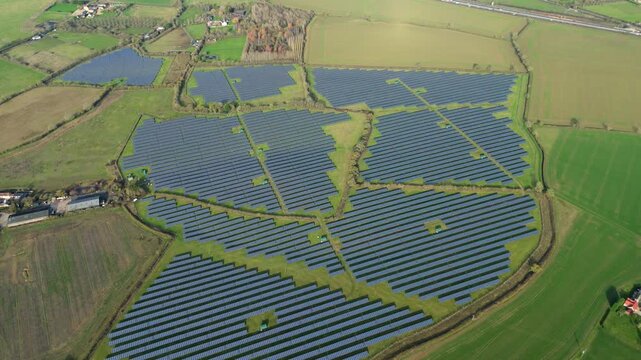 High angle aerial view tracking past thousands of blue solar panel modules on a sunny day