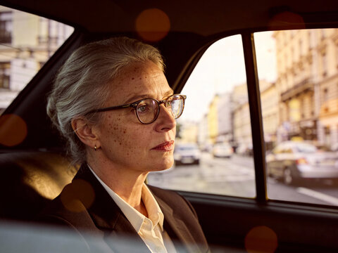 Portr&auml;t einer eleganten Frau mit Brille und grauen Haaren im Auto