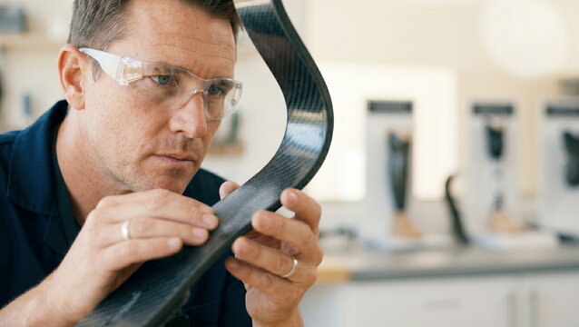 Prosthetic component examination of carbon fiber blade in workshop for quality control, biomedical engineering innovation.