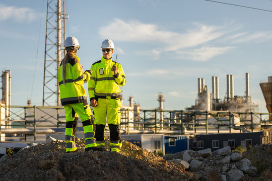 Engineer team monitoring production data at oil and gas facility, Technician using digital tablet at oil refinery plant, Industrial worker in safety gear reviewing project plans at petrochemical plant