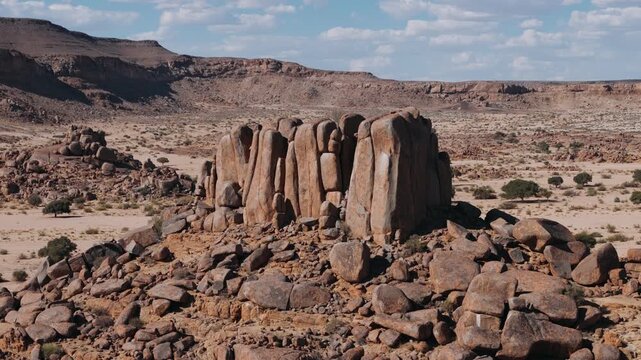 Aerial view of a massive rock formation in the arid, sandy desert landscape of damaraland, namibia, on a sunny day