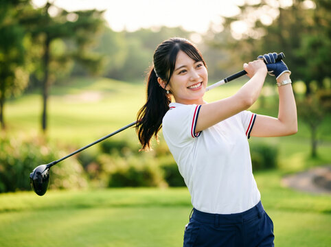 ゴルフ場でドライバーショットのフィニッシュを決めて笑う女性