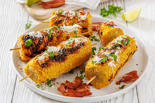 Sweetcorn skewers on a plate have grated cheese