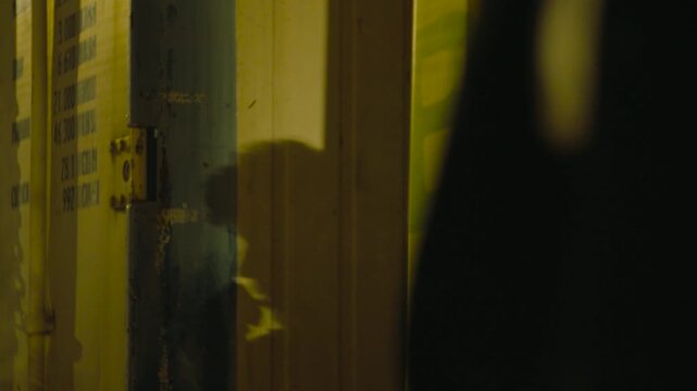 Shadow of a person smoking a cigarette projected onto a yellow industrial cargo container