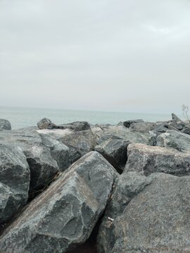 Rocky seaside landscape with calm water and overcast sky creating a peaceful mood.