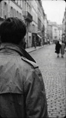 Naklejka premium Black and white photograph of a solitary man walking through an old cobblestone street, capturing loneliness, nostalgia, and urban cinematic atmosphere.