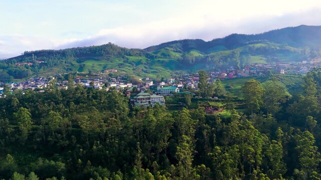 Scenic Aerial View of Green Mountain Landscape Surrounding a City Center with Urban Buildings, Lush Hills, Natural Environment, Cloudy Sky, Modern Development and Beautiful Cityscape Between Mountains