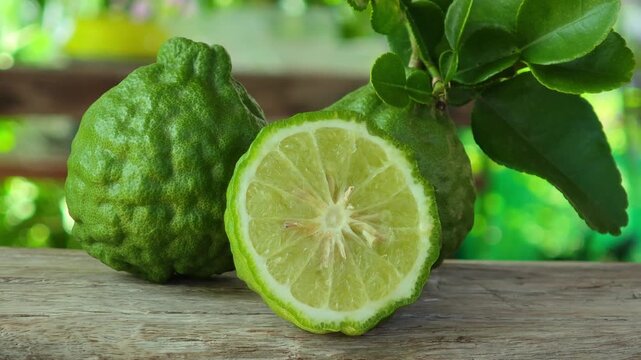 Fresh kaffir lime fruits with leaves on wooden table background.