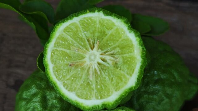 Fresh kaffir lime fruits with leaves on wooden table background.