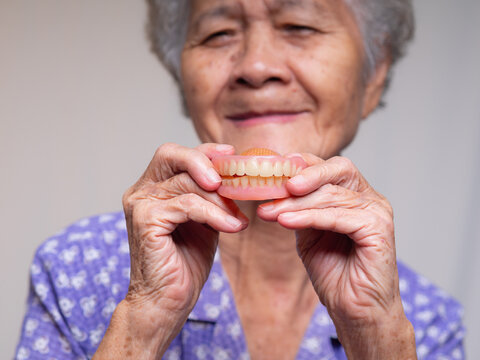 Senior woman holding dentures and smiling without them