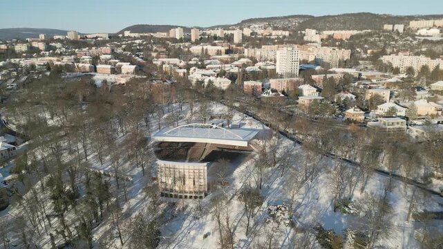 An elevated drone winter view of the open-air summer cinema in &Uacute;st&iacute; nad Labem shows rows of empty, snow-covered amphitheater seating and a large projection screen under a massive metal roof structure 