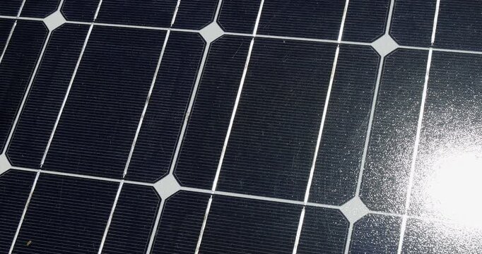 Close up zoom look of a modern solar panel texture illuminated by bright direct sun light while generating clean renewable energy