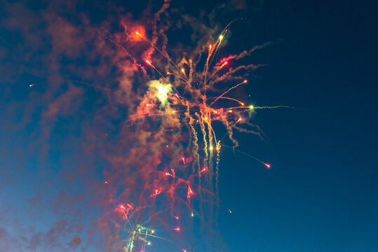 Colorful festive pyrotechnics fireworks burst celebrating New Year or Independence Day. Vibrant multi-color fireworks exploding against a dark blue twilight sky.