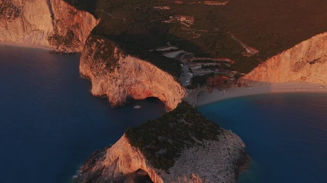 Panoramic drone view of Porto Katsiki at sunset. Golden light bathes the white cliffs, iconic beach and turquoise Ionian Sea in Lefkada, Greece.