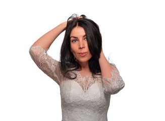 Naklejka premium A beautiful young woman with long dark hair wears an elegant white lace dress while running her hands through her hair against a plain white background.