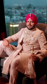 Vertical Shot of Royal Sikh Groom Sitting on Sofa with Kirpal Smiling in the Camera