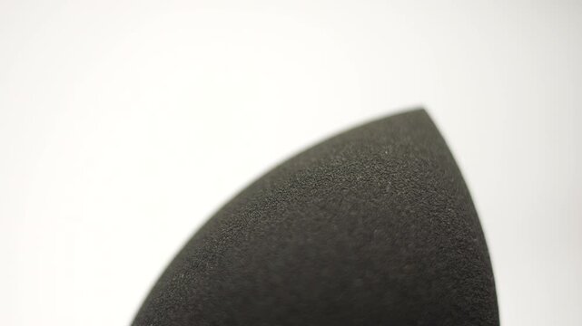 50p extreme close up macro shot of a black makeup sponge rotating to reveal texture