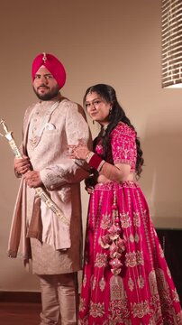 Vertical Shot of Sikh Bride and Groom Posing in Camera in Wedding Attire