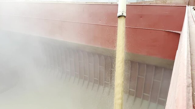 wheat loading to ship hold by pipe. slow motion. vessel cargo compartment. grain dust.