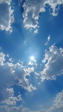 Bright sun shining through scattered white clouds in a clear blue sky.
