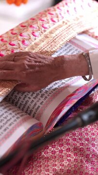 Vertical Close Up of Sikh Priest Reading Guru Granth Sahib During Wedding Ceremony
