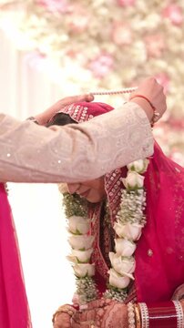 Vertical Shot of Sikh Groom Putting White Rose Varmala On Bride During Traditional Wedding Ceremony