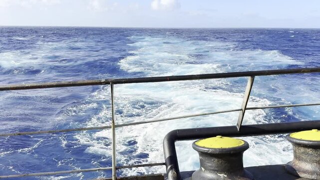 astern of cargo ship underway at ocean. keel and propeller jet till horizon. mooring rollers. ship stern.