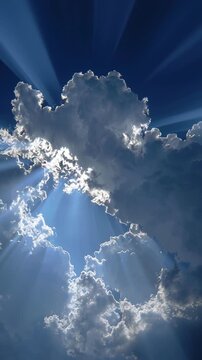 Dramatic sunlight rays breaking through thick silver-lined clouds in a bright blue sky.