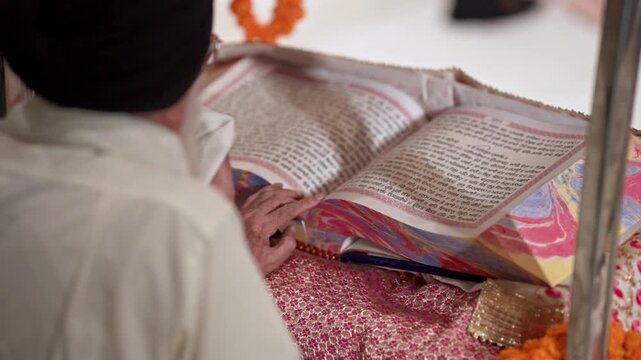 Over the Shoulder Shot of a Sikh Priest Reading Gurbani from the Guru Granth Sahib
