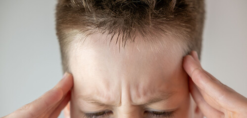 Fototapeta premium Young boy struggling with head pain, reflecting common health issues and mental pressure in adolescence, health issue, youth pain