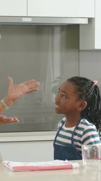 Vertical video: Receiving gran's hug kid in apron listening to learn and touching towel at kitchen