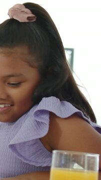 Vertical video: Framing girl in lilac top fixing scrunchy leaning to see kitchen w or  OJ, copy spac
