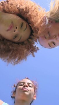 Vertical video: Waving 3 pals leaning over cam at pool for selfie posing in swimwear blowing kisses