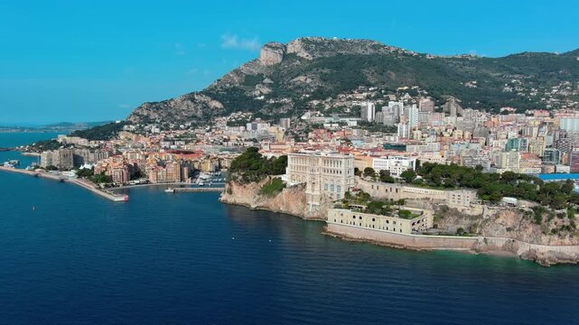 Aerial view of Monaco-Ville coastline. Cinematic drone orbit of Monaco's Oceanographic Museum on cliffs with Monte Carlo skyline and Mediterranean Sea during a sunny day. 