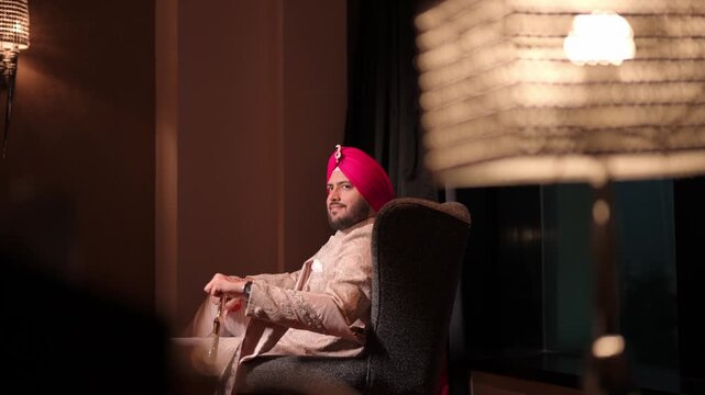 Handsome Punjabi Groom In Traditional Sherwani And Pink Turban Relaxing Before Wedding