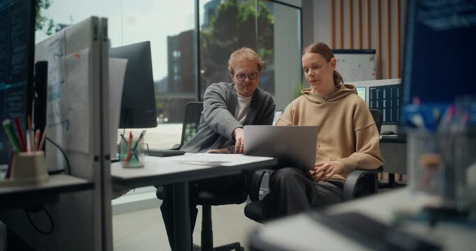 Software Development Team of Two Talk, Use Laptop in a Modern Office, Writing Code, App Design, AI Use, Cybersecurity and Project Goals Through Focused Lead and Teamwork and Planning.
